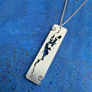 A stainless steel rectangular-shaped necklace pendant featuring a cut-out shape of Lake Champlain, with wave curl accents, by Close 2 UR Heart.