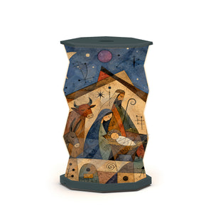 A sculptural, hexagonal side table or lamp featuring a faceted, twisted design covered in an abstract, geometric art print. The print depicts figures and star-like motifs in warm earth tones of brown, beige, and orange, set against a dark charcoal/black base and top surface, photographed on a clean white studio background.