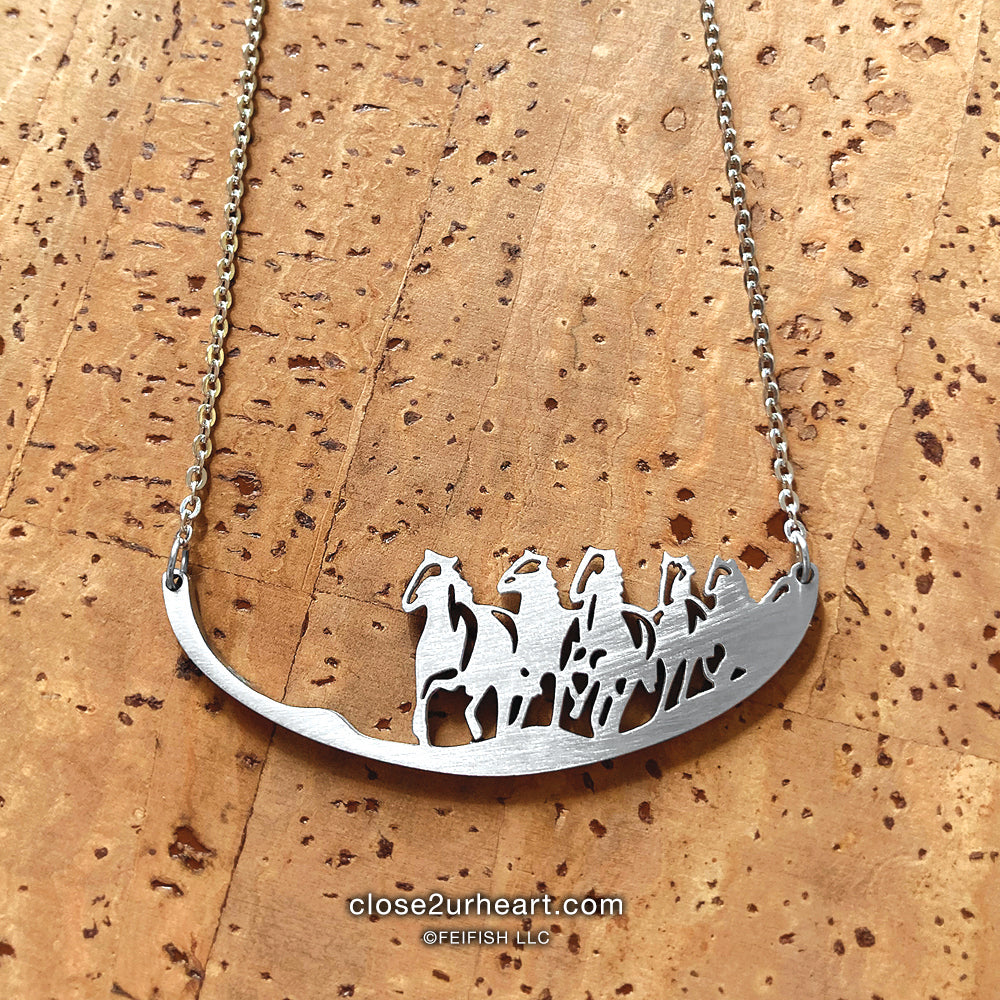 A stainless steel necklace featuring a group of wild horses running toward the viewer.